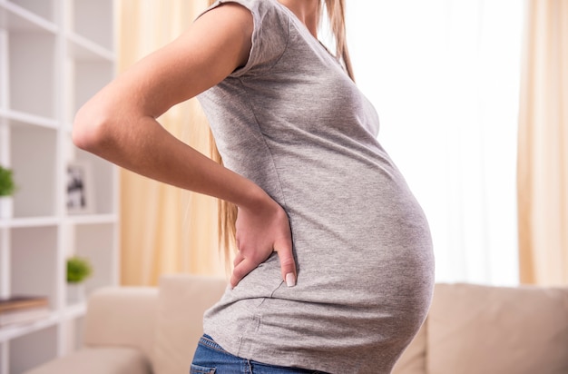 Pregnant woman with hands over tummy at home.