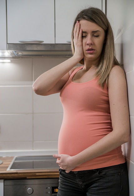 두통 및 통증 임신 한 여자입니다. 젊은 임신 한 여자는 집에서 나쁜 느낌. 강한 통증으로 임신 한 여자