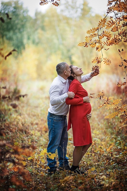 Pregnant woman with her husband in the autumn park