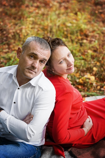 Foto donna incinta con suo marito nel parco autunnale