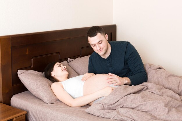 Pregnant woman with her husband in bed in the morning