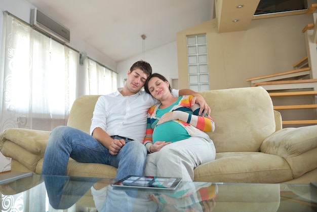 pregnant woman with her husband have fun relax and using tablet comture at modern home