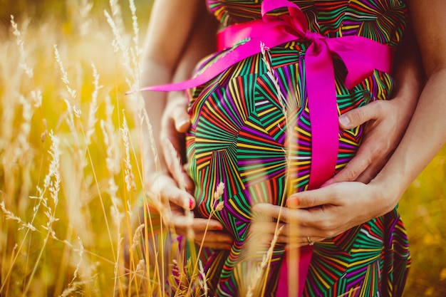 Pregnant woman with her husband hugging her belly