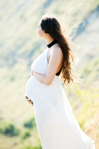 写真 長い健康な ⁇ と花を持つ妊婦 美しい女の子が赤ちゃんを待っています