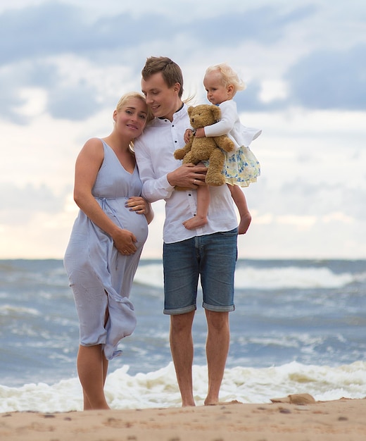 pregnant woman with man and daughter at beach