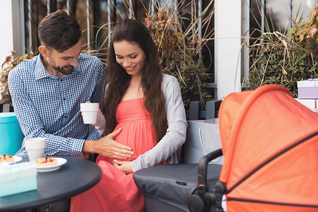 Pregnant woman with a man is sitting at a cafe table