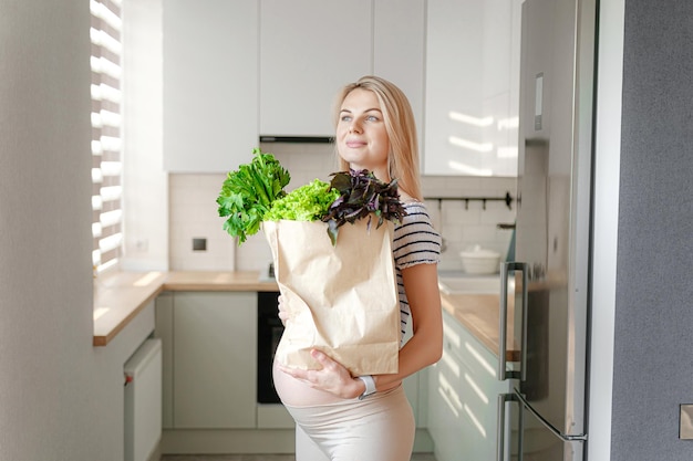 Pregnant woman with packages of fresh herbs green smoothies the concept of wholesome and healthy food for pregnant women