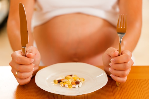 Фото Беременная женщина с тарелкой, полной таблеток