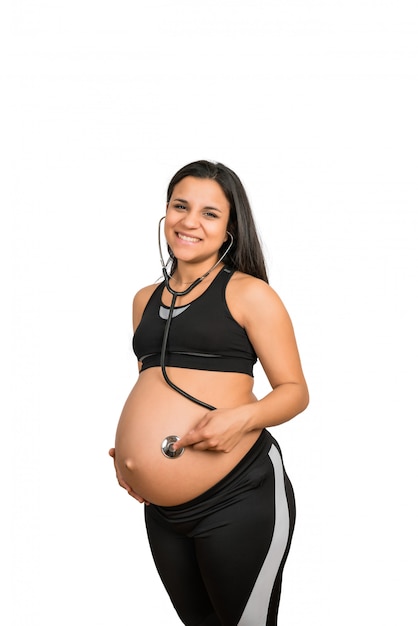 Pregnant woman with stethoscope on belly listening to the baby..