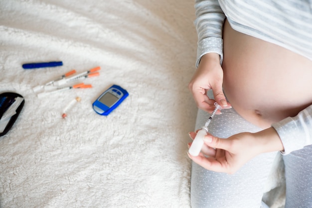 Pregnant woman with syringe, diabetes at home concept