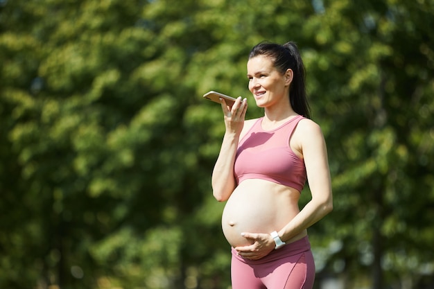 Pregnant woman with telephone outdoors