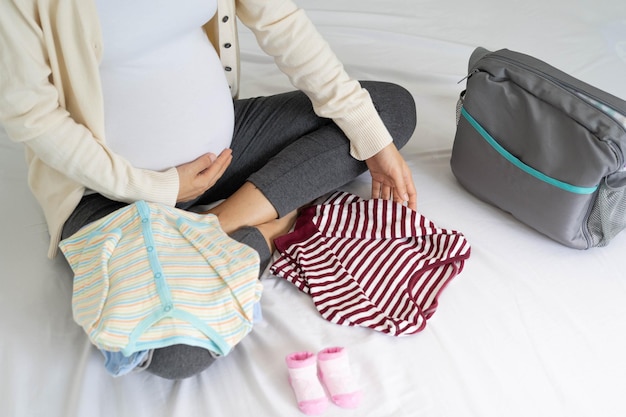 Le donne incinte sono felici di preparare vestiti per bambini borse da imballaggio per andare in ospedale