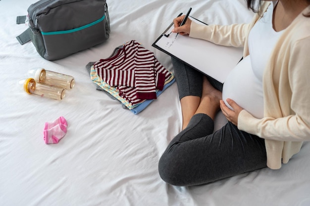 Le donne incinte sono felici di preparare vestiti per bambini borse da imballaggio per andare in ospedale