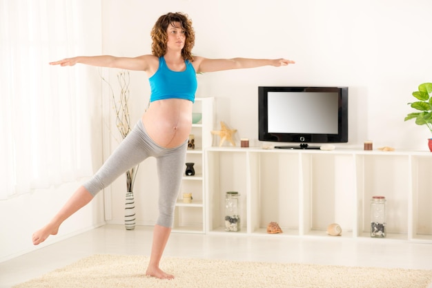 Pregnant women in sportswear, doing exercises in the living room.