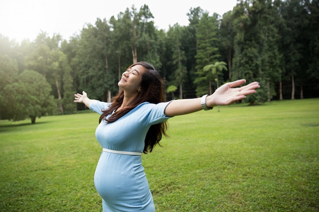 Pregnant young woman enjoying the nature with open arms and clos