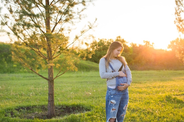 Pregnant young woman hugging her stomach outdoors