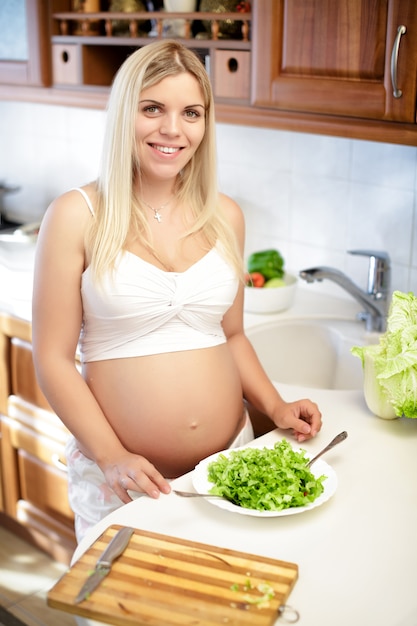 Pregnant young woman mixing salad in a bowl