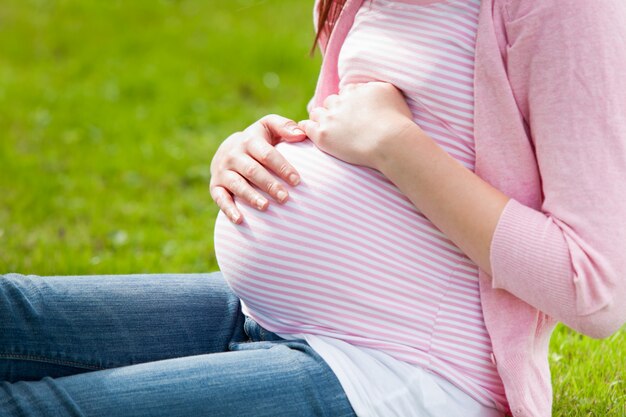 Pregnant young woman sitting on the grass