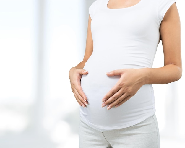 Pregnant young woman in white t shirt on  background