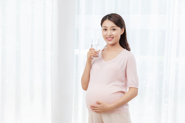 水のガラスと妊娠中の若い女性