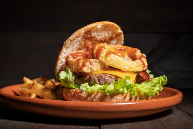Premium kwaliteit burger met uienringen kaas en barbecuesaus geserveerd met frietjes op een rustiek bord Hoge kwaliteit fotografie