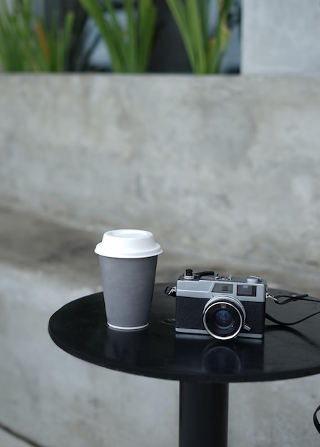 写真 テーブルにカメラを置いたプレミアム紙コップのモックアップデザイン