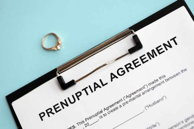 Photo prenuptial agreement and wedding ring on table premarital paperwork process close up