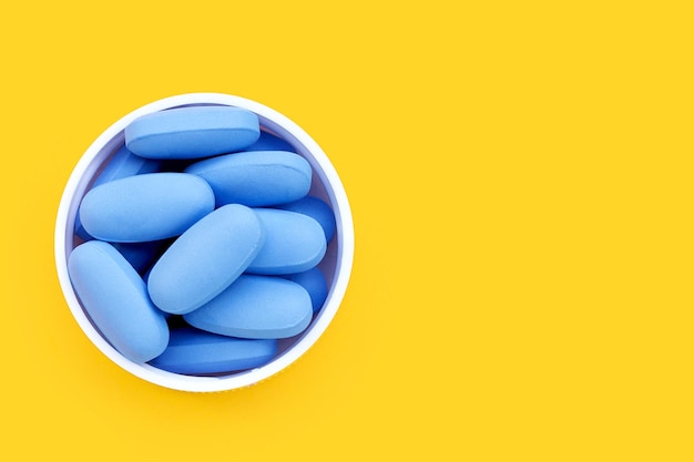 PrEP PreExposure Profylaxe blauwe pillen gebruikt om HIV te voorkomen Blauwe pillen in plastic doppen op gele achtergrond