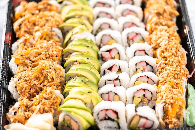 Prepackaged variety of sushi and sushi rolls in a plastic tray