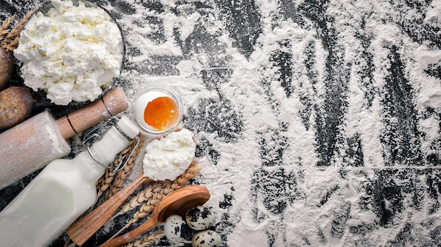 Preparation for baking cheese sour cream milk flour eggs On a black wooden background Top view Free space