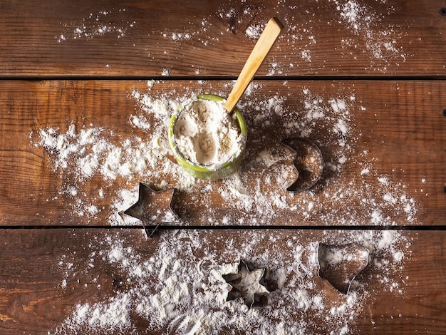 Preparation for baking holiday cookies flour in a clay jar and silicone shaped tin molds on a wooden table svnrhu view