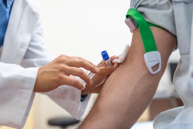 Preparazione per l'analisi del sangue da parte di una dottoressa uniforme medica sul tavolo in una stanza bianca e luminosa l'infermiera perfora la vena del braccio del paziente con un tubo vuoto dell'ago