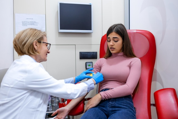 Preparation for blood test by female doctor medical uniform on the table in white bright room Nurse pierces the patient's arm vein with needle blank tube