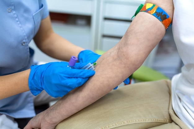 Preparation for blood test with pretty young woman by female doctor medical uniform on the table in white bright room Nurse pierces the patients arm vein with needle blank tube