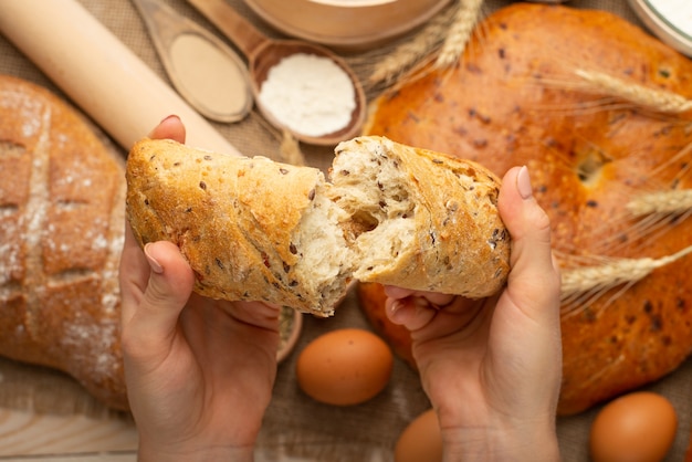 La preparazione di pane, pane fresco in primo piano delle mani su fondo di legno vecchio, concetto per la cottura