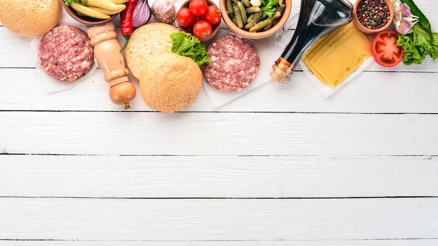 Preparation of burger Meat tomatoes onions On a white wooden background Top view Free copy space