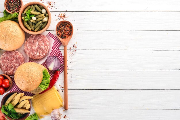 Preparation of burger Meat tomatoes onions On a white wooden background Top view Free copy space