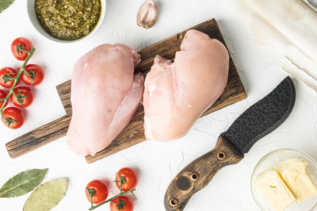 Preparation of chicken kiev from chicken breast stuffed with herbs on white stone background top view flat lay