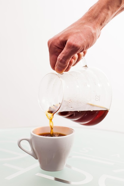 Foto preparazione di una tazza del filtro del caffè sulla caffettiera del tavolo in mano