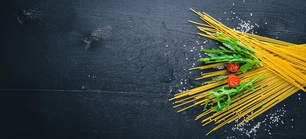 Preparation for cooking Pasta arugula leaves and tomatoes On a wooden background Top view Free space for your text