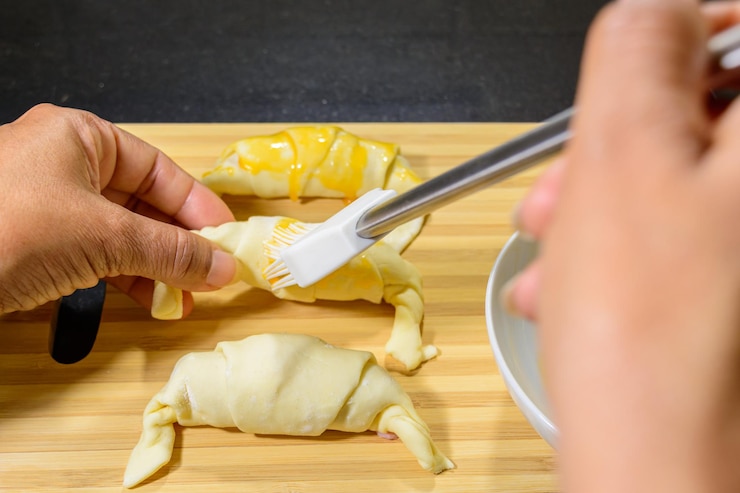 Photo preparation croissants with ham and cheese and painted with egg yolk on a wooden board ready to bake
