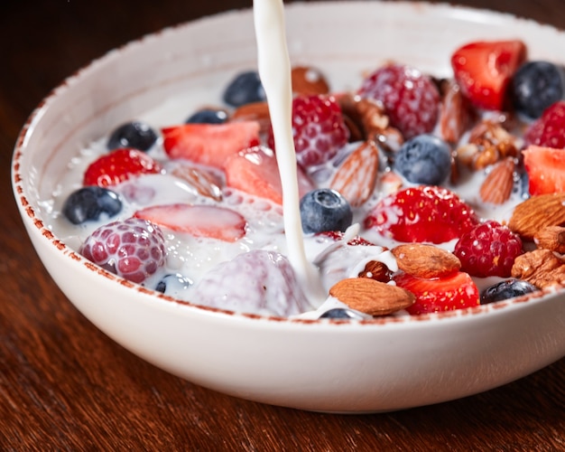 Preparazione della colazione dietetica naturale con ingredienti biologici freschi bacche di noci di muesli miele