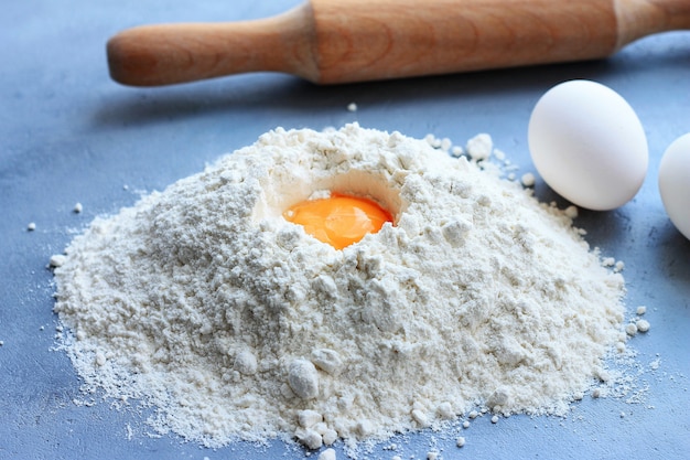 Preparation of dough, flour, eggs and rolling pin on gray background.