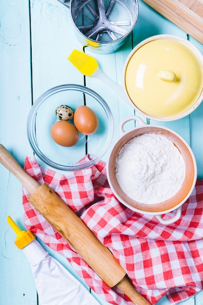 Preparation of the dough. Ingredients for the dough - Eggs and flour with a rolling pin. On wooden background.