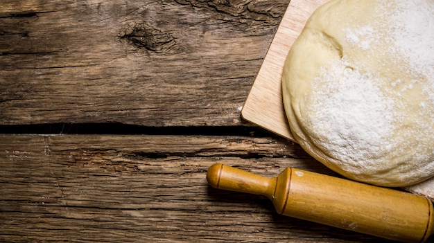 Preparation of the dough The prepared dough with a rolling pin on a wooden table