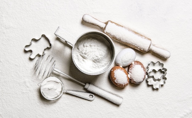 Preparation of the dough. Tools for dough - a rolling pin, whisk, sieve, moulds in flour.  Top view