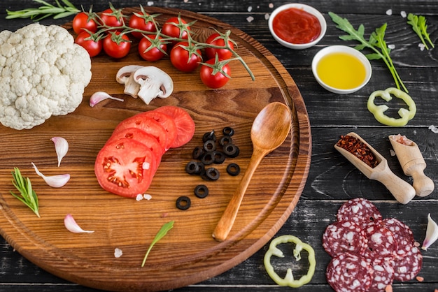 Preparation of the dough and vegetables to production of pizza. Ingredients for production of pizza on a wooden background