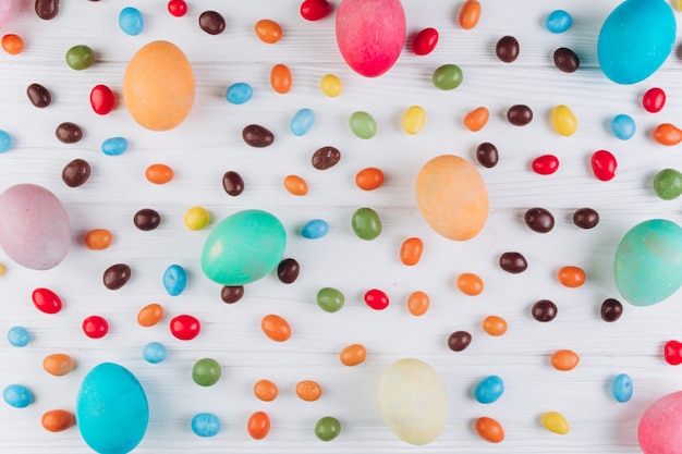 Preparation for Easter. Сolored eggs and candy on a white wooden background