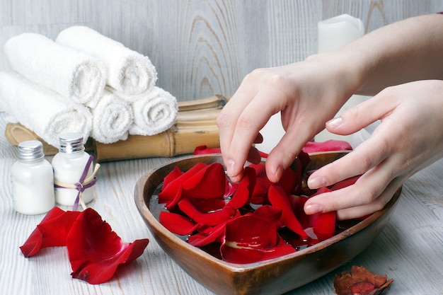 빨간 장미 꽃잎과 흰색 액세서리가있는 손을위한 스파 절차 준비