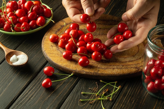 Photo preparation of fruit drink from cherries chef sorting cherry berries before preparing a sweet drink in a jar sweet berries for the diet